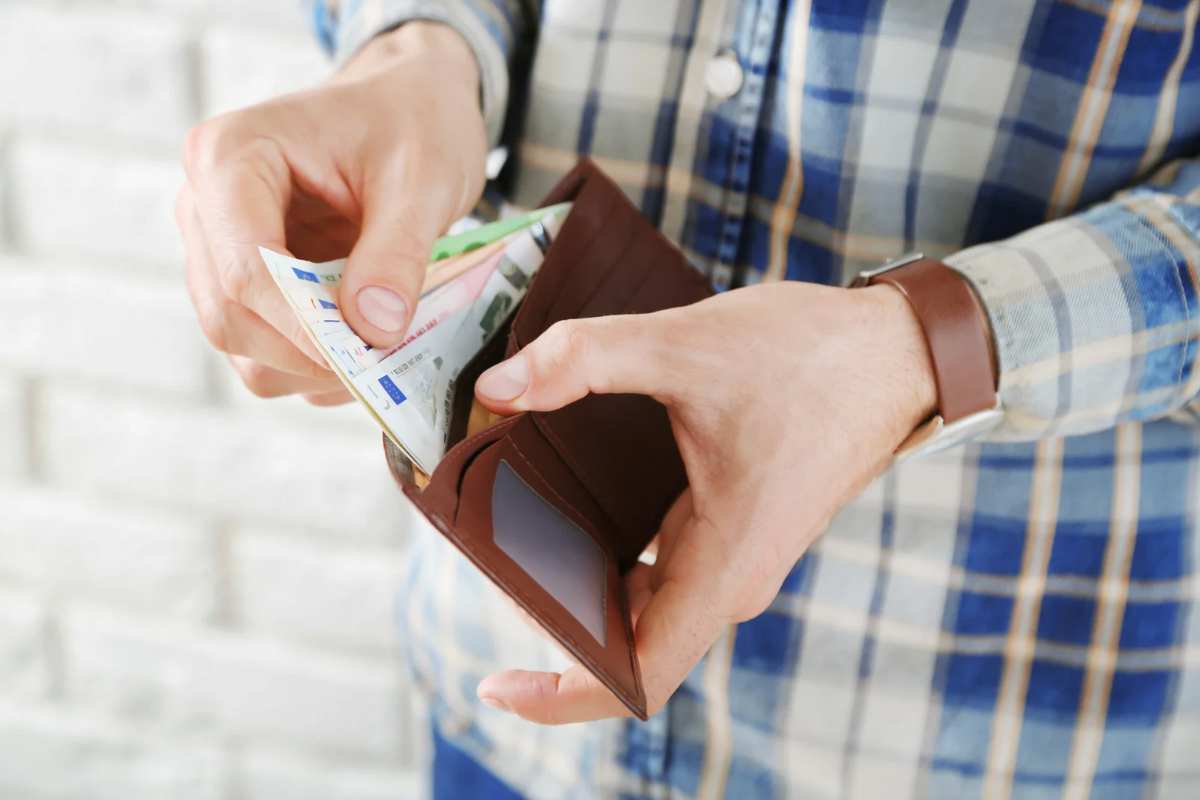 Uomo che tira fuori banconote euro dal portafoglio