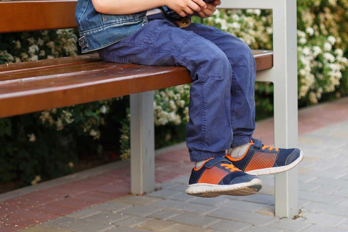 gambe di un bambino seduto su una panchina