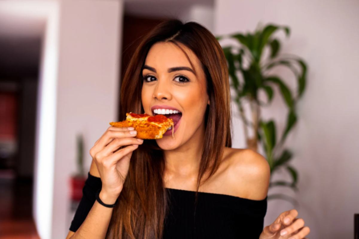 donna che mangia una fetta di pizza