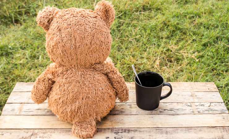 Orsacchiotto in giardino con una tazza