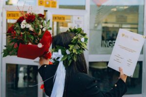 ragazza laureata di spalle con tesi e mazzo di fiori