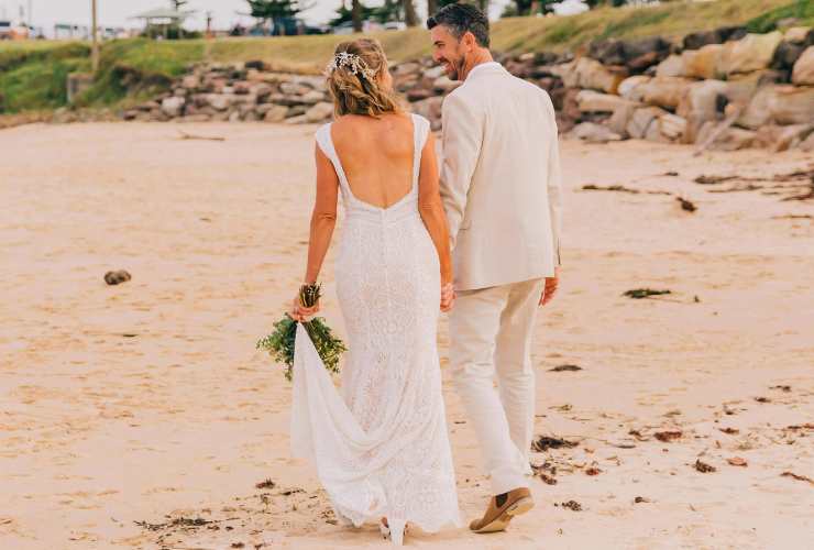 coppia di sposi passeggia in riva al mare