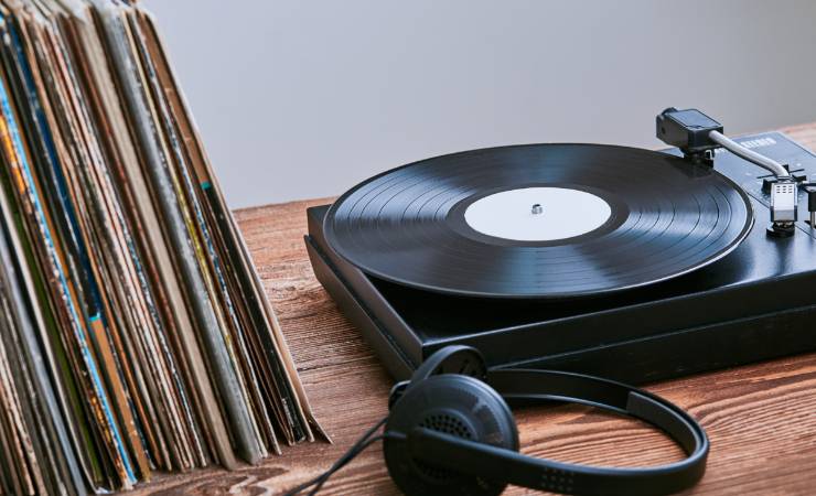 Vinile nel giradischi, con custodie accanto e cuffie